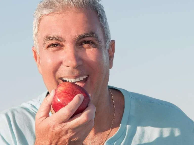 Older man biting into a red apple